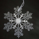 Acrylic Snowflake Christmas Decorations Transparent Tree Pendants hanging on a snowy Christmas tree. Ideal for DIY holiday decor and winter themes.